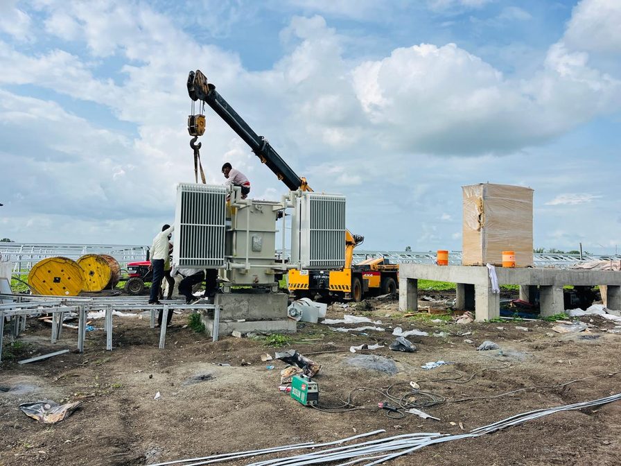 Crane placing a transformer beside inverter cabinets